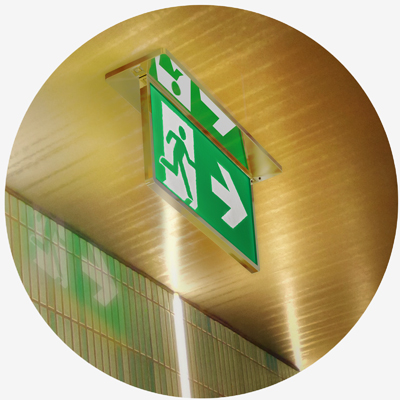 Slim exit sign with gold trim mounted to ceiling