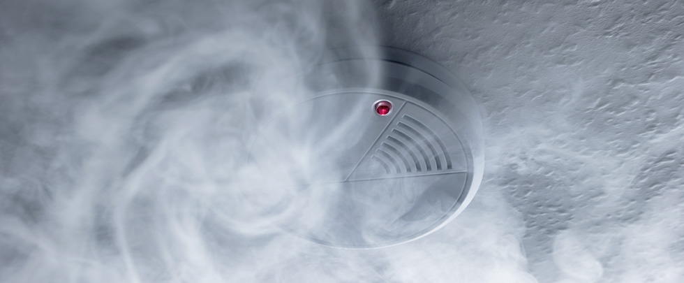 Smoke alarm on ceiling, smoke around it