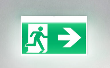 Green emergency exit sign mounted on wall